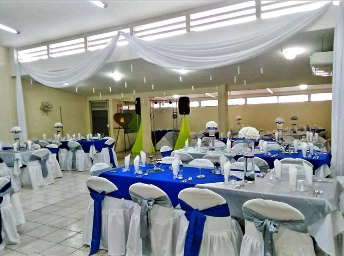 Techo de tela azul y blanco en salón techado, con sillas de lazo azul rey y plateado