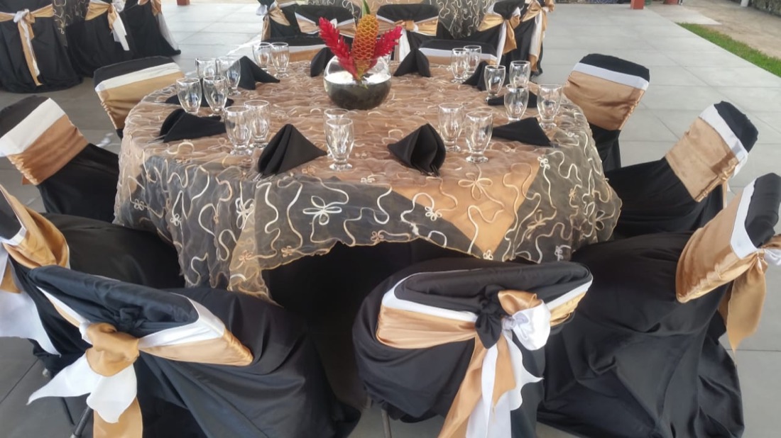 Mesa redonda dorado y negro estampado, sillas negras con lazo tricolor dorado, blanco y negro