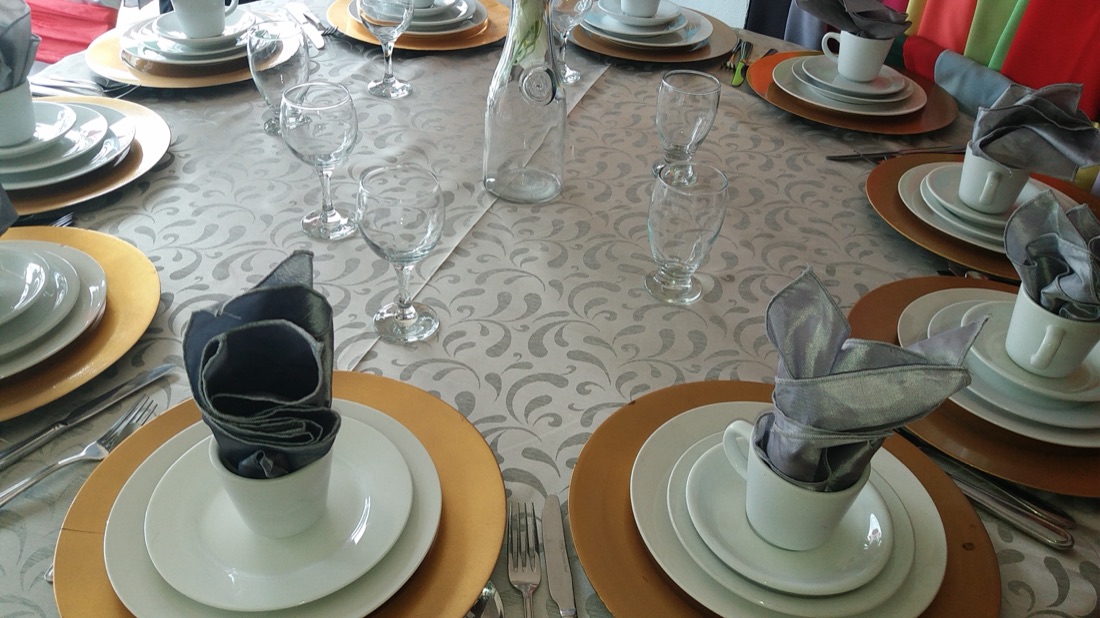 Mesa navideña roja y verde con platos base dorados y centro de mesa navideño