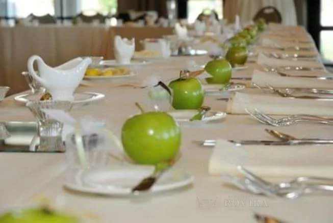 Mesa larga vestida en blanco con salseras de porcelana, cristalería y manzanas verdes como detalle