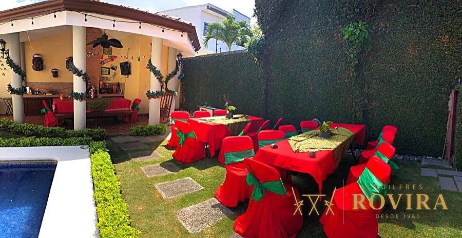Montaje navideño en jardín junto a piscina, forros de silla rojos con lazo verde