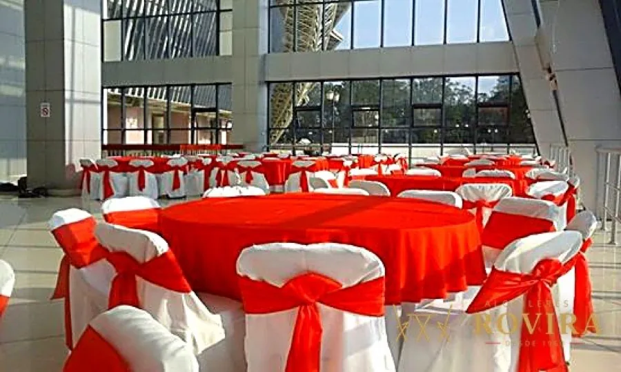 Atrio de edificio corporativo con mesas rojas y lazos blancos