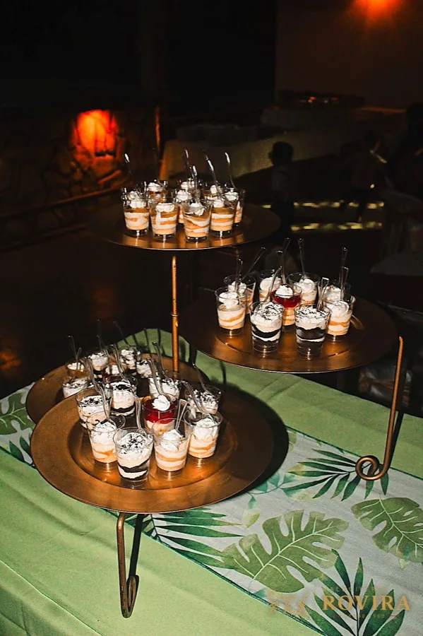 Postres individuales en vasitos sobre exhibidor de tres niveles color bronce
