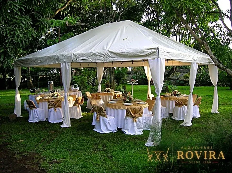 Toldo blanco con mesas redondas doradas en jardín