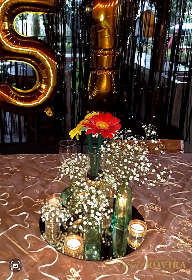 Centro de mesa de XV años con globo dorado en forma de número, flores gerbera y velas