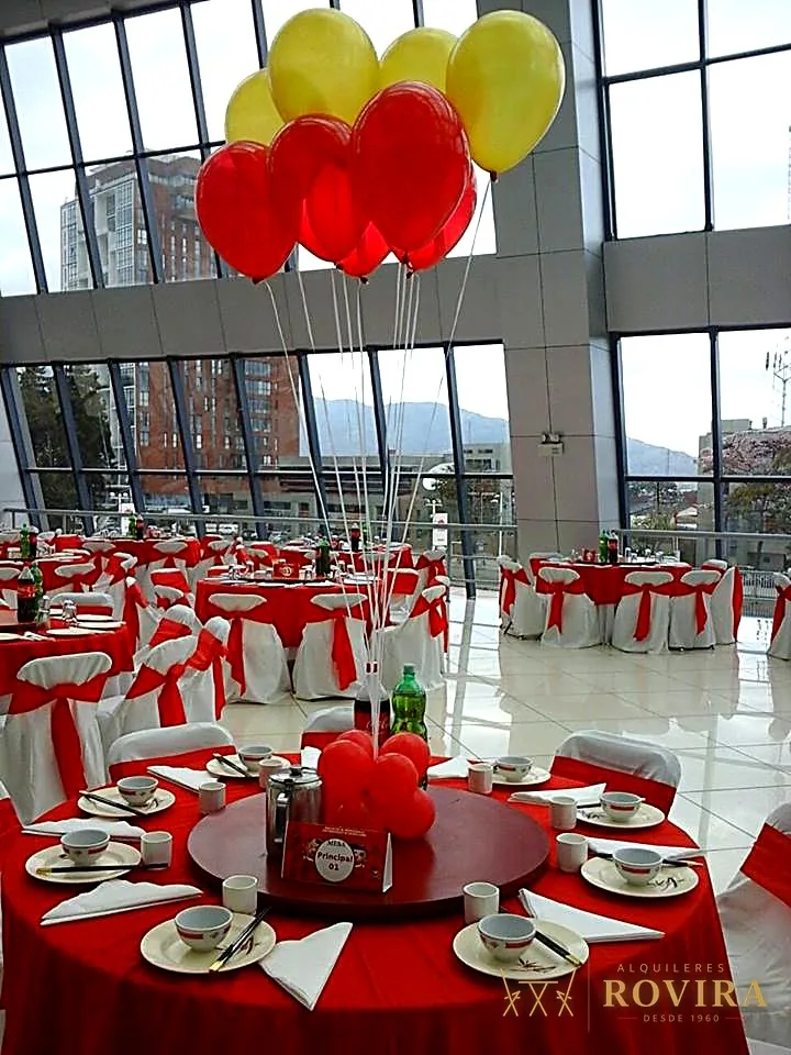 Evento corporativo en salón con vista a la ciudad, mesas decoradas y globos